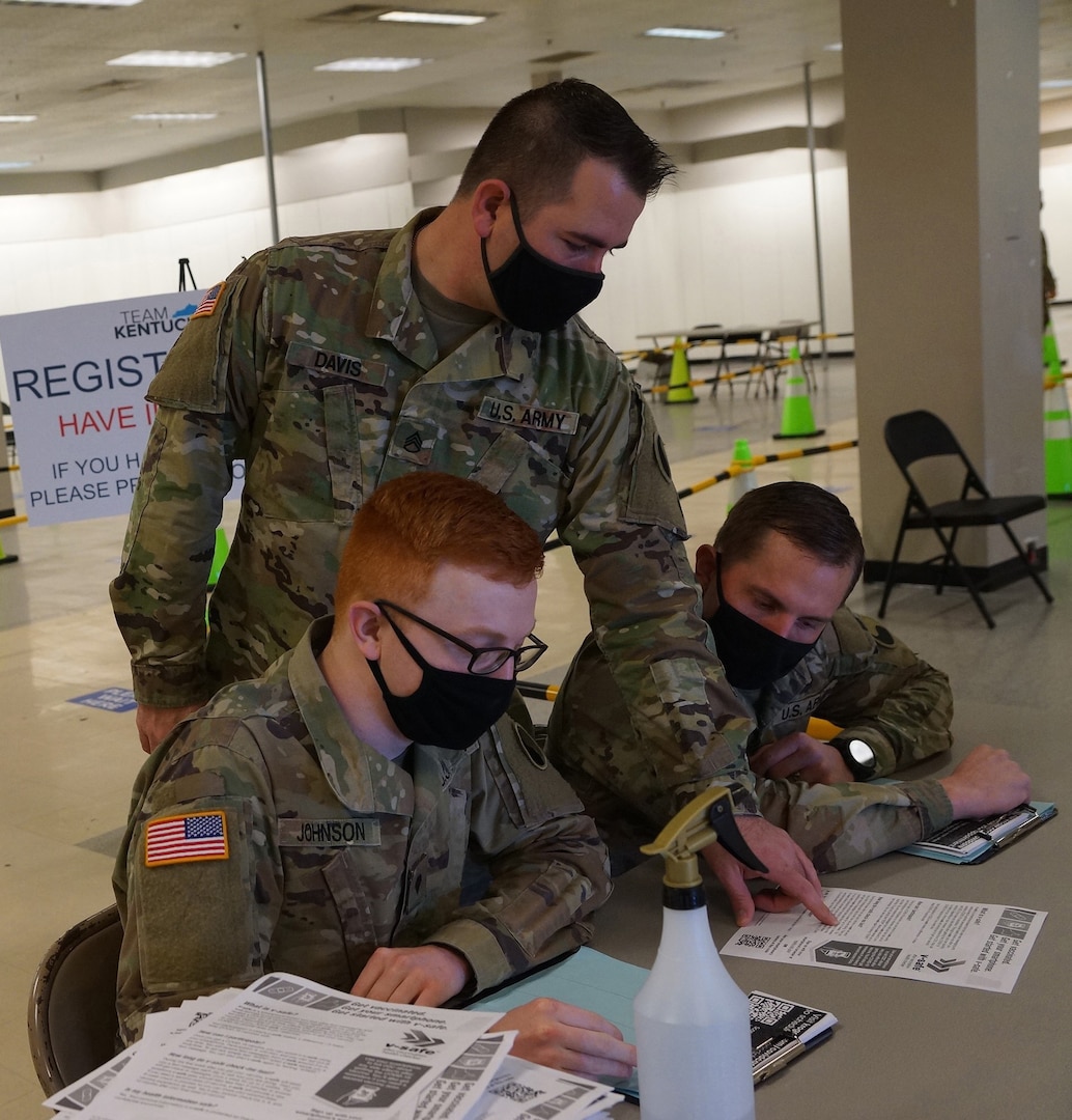 Kentucky Army National Guard Staff Sgt. Patrick Davis reviews paperwork with Pfc. Mitchell Johnson, left, both with Headquarters and Headquarters Company, 1st Battalion, 149th Infantry Regiment, and Sgt. Shane Moody with Alpha Company, 1-149th IN, in Bowling Green, Ky., March 6, 2021. The Soldiers are a part of the local area's COVID-19 vaccine rollout.