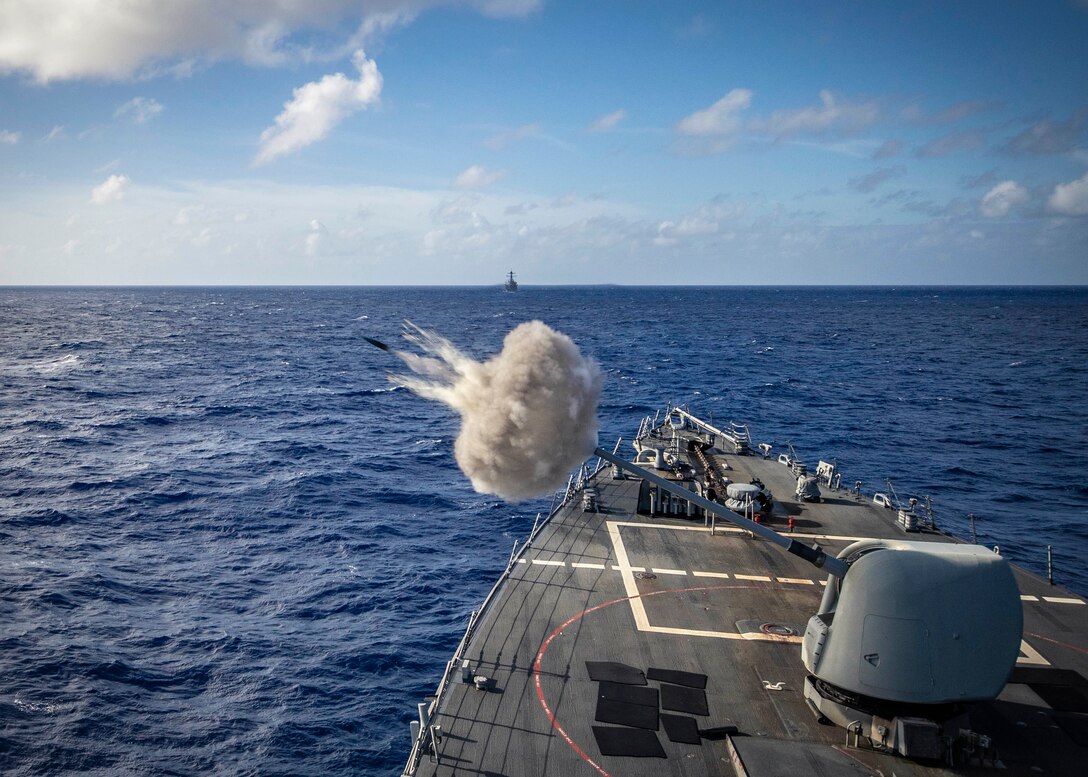 A ship fires a 5-inch gun during a live-fire gunnery exercise at sea.