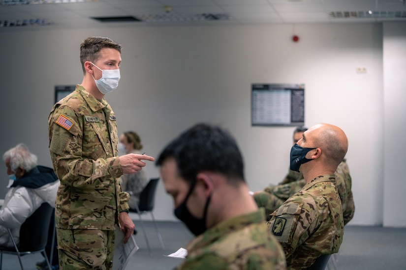 An Army doctor instructs soldiers who are waiting to be vaccinated.