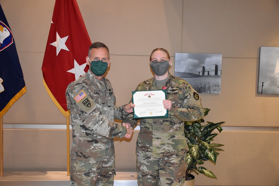 Army sergeant receives award from Army general.