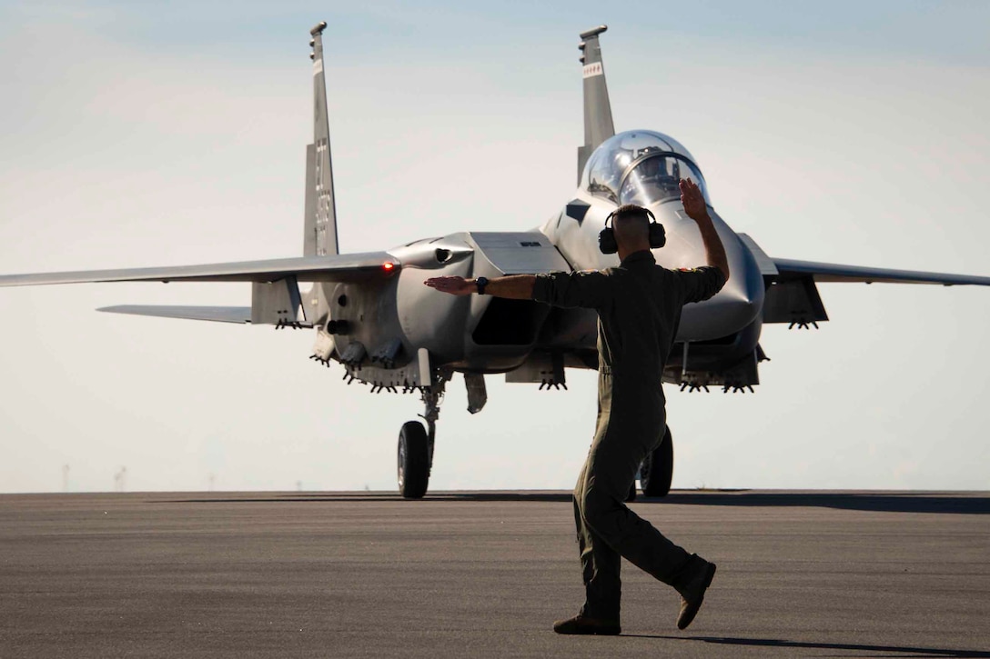 An airman signals at an aircraft.