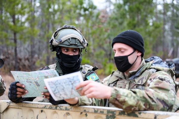 Two soldiers hold maps in their hands and talk.