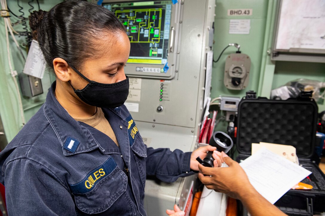 A woman holds a small piece of equipment in one hand.