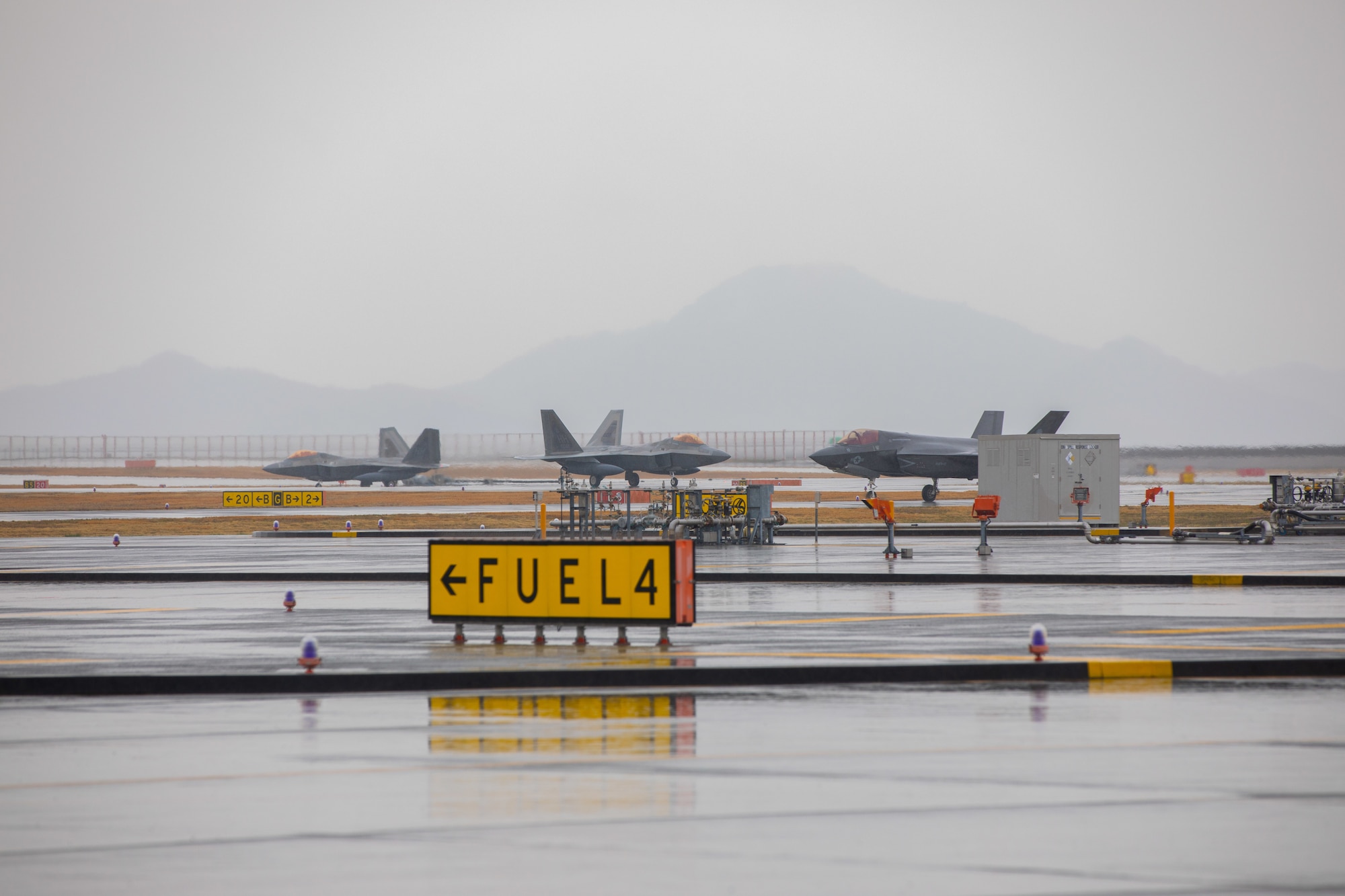 A U.S. Marine Corps F-35B Lightning II Aircraft with Marine Fighter Attack Squadron 121 and Air Force F-22 Raptors with the 199th Fighter Squadron taxi on the flight line at Marine Corps Air Station Iwakuni, Japan, March 12, 2021. Airmen with the 199th Fighter Squadron and the 19th Fighter Squadron, based out of Joint Base Pearl Harbor-Hickam, Hawaii, deployed to MCAS Iwakuni to conduct local area training with U.S. Marine Corps units. This training event is designed to support a free and open Indo-Pacific by providing global reach and agility throughout the region. (U.S. Marine Corps photo by Lance Cpl. Triton Lai)