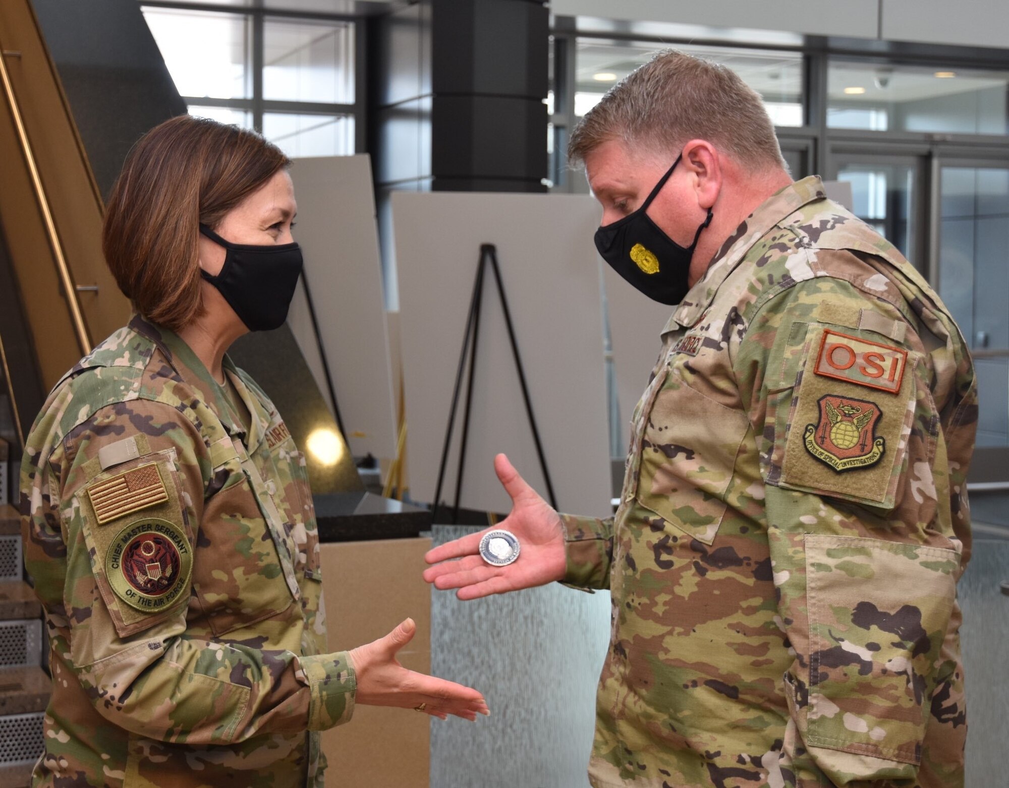 Office of Special Investigations Commander, Brig. Gen. Terry L. Bullard, presents his coin to Chief Master Sergeant of the Air Force JoAnne S. Bass, during her inaugural visit to OSI Headquarters March 12 as 19th CMSAF, and the first woman in history to serve as the highest-ranking noncommissioned officer of a U. S. military service branch. (Photo by SA Spencer King)
