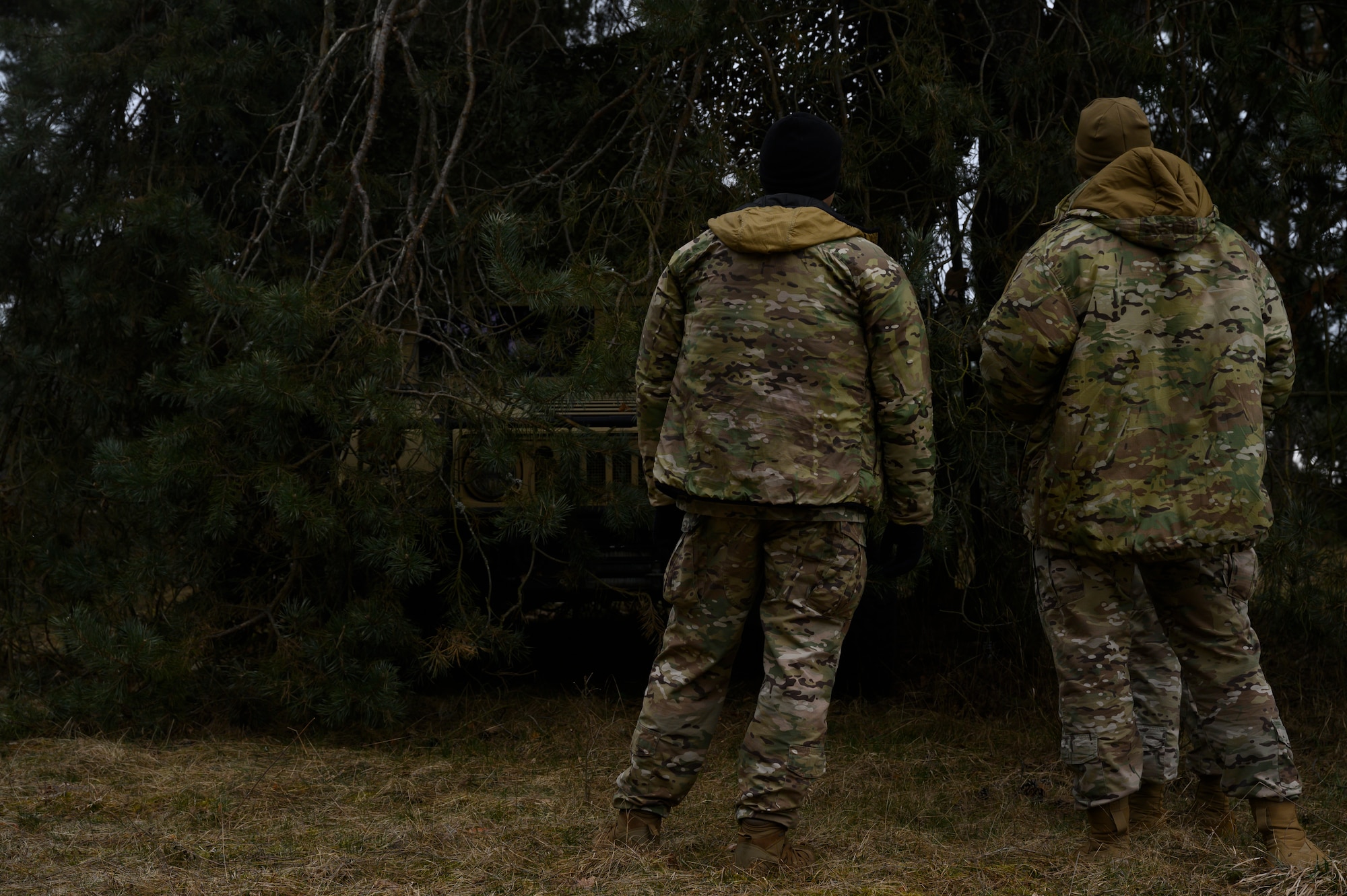 Two Airmen look on at a Humvee.