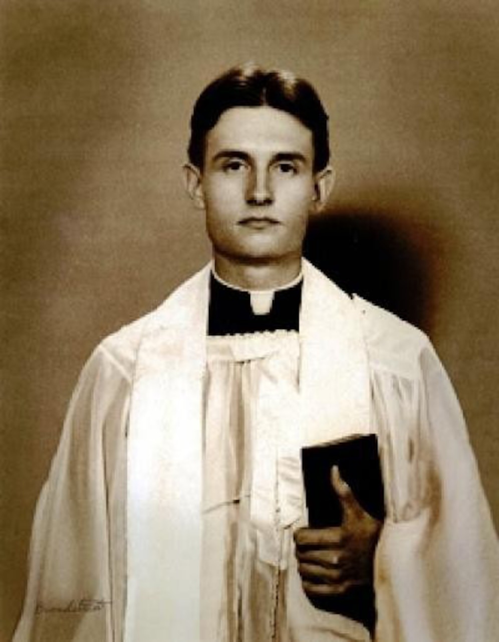 A man in liturgical dress holds a Bible.