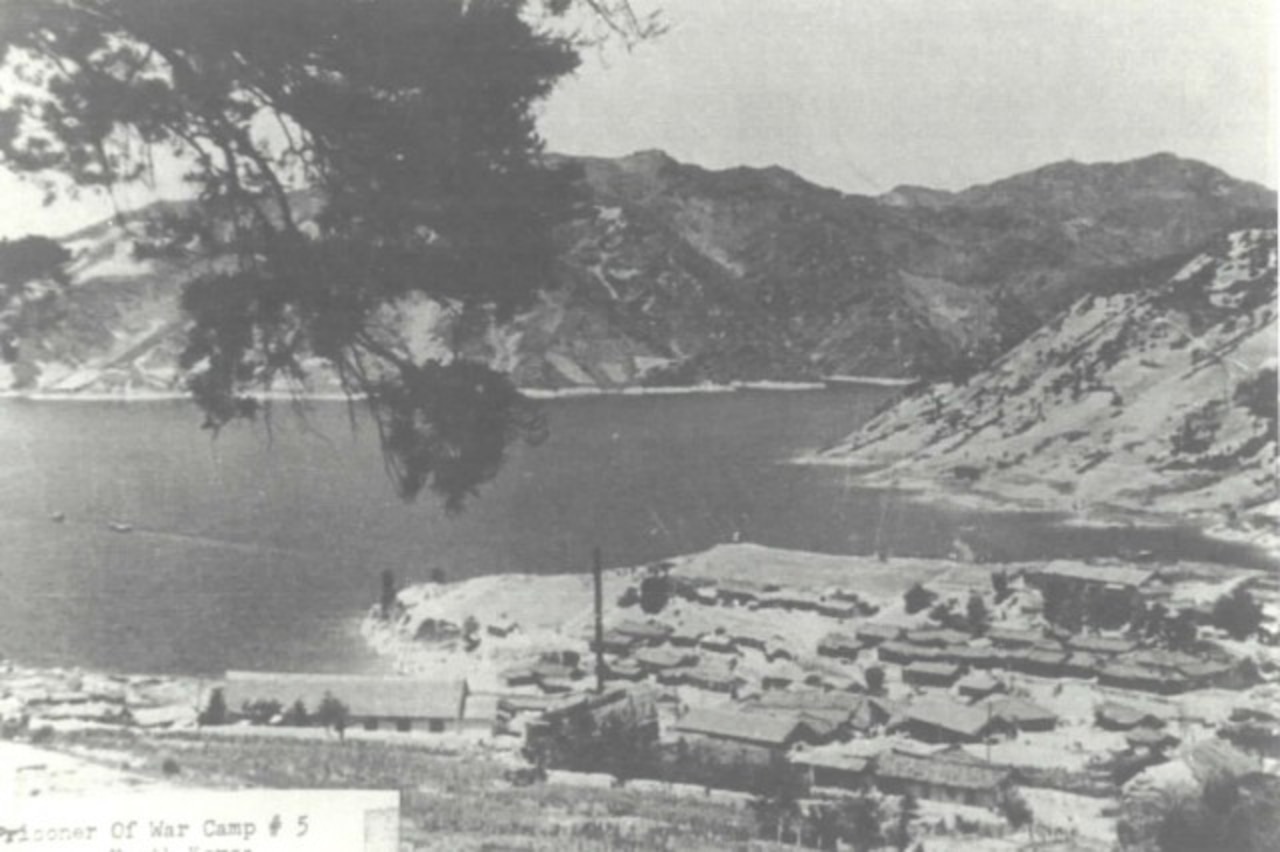 Buildings sit on the shore of a mountainous inlet.