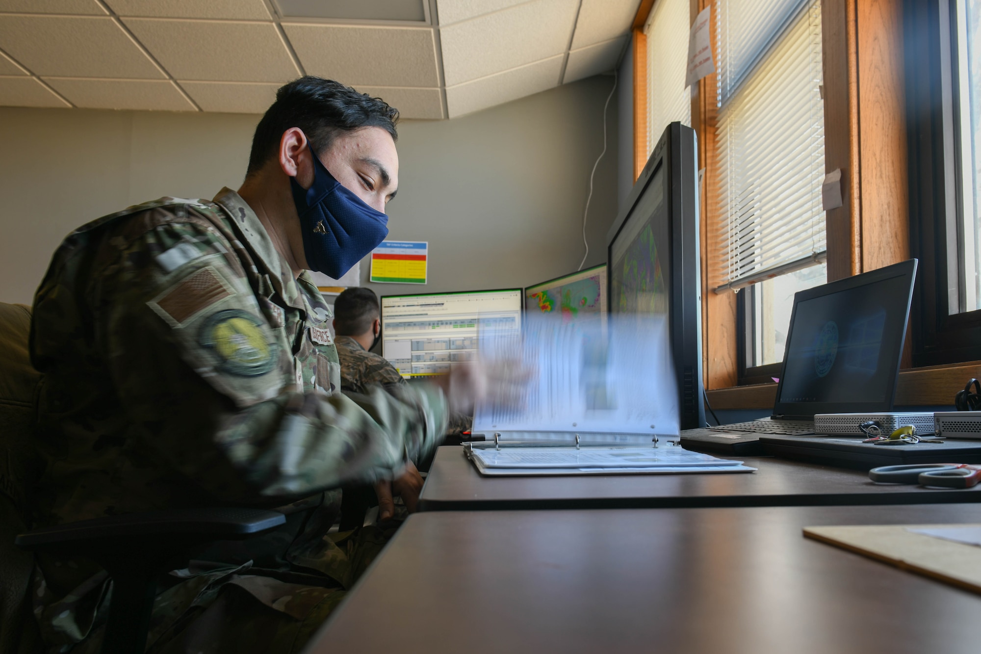 Airman 1st Class Kyle Carpenter, 22nd Operations Support Squadron weather forecaster, looks through forecast reference material March 3, 2021, at McConnell Air Force Base, Kansas. The reference material is made up of meteorological techniques based on season specific weather regimes over the United States. It also contains local forecasting techniques based on topography and effects particular weather systems have on McConnell AFB. (U.S. Air Force photo by Senior Airman Nilsa Garcia)