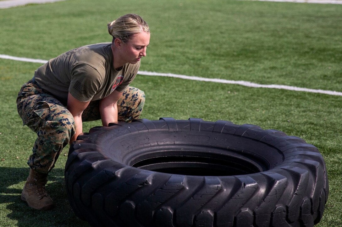 A Marine flips a tire.