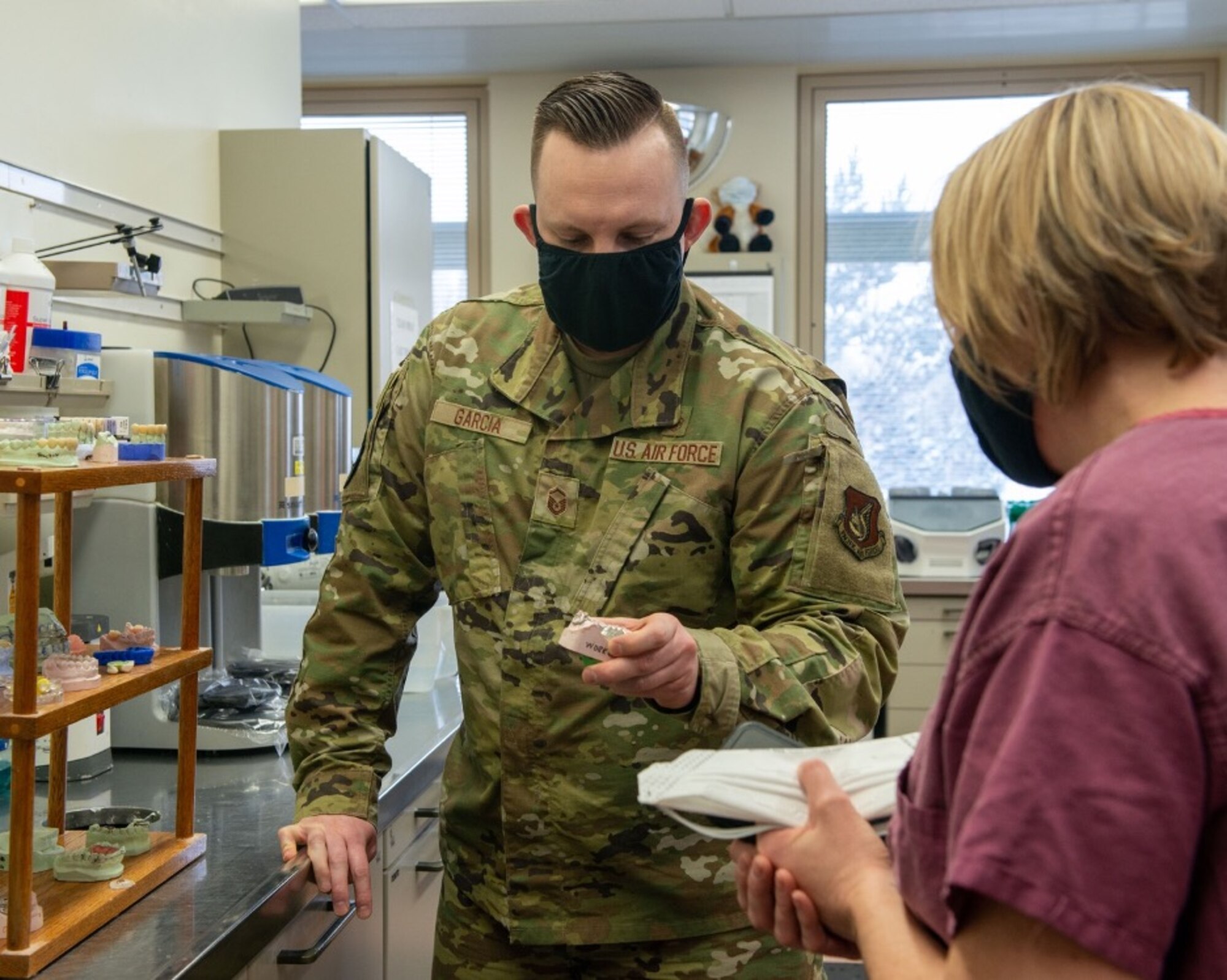 U.S. Air Force Master Sgt. Matthew Garcia, left, a dental lab technician assigned to the 673d Dental Squadron, shows fabricated crowns to U.S. Air Force Col. Kirsten Aguilar, Joint Base Elmendorf-Richardson and 673d Air Base Wing commander, at JBER, Alaska, March 2, 2021.