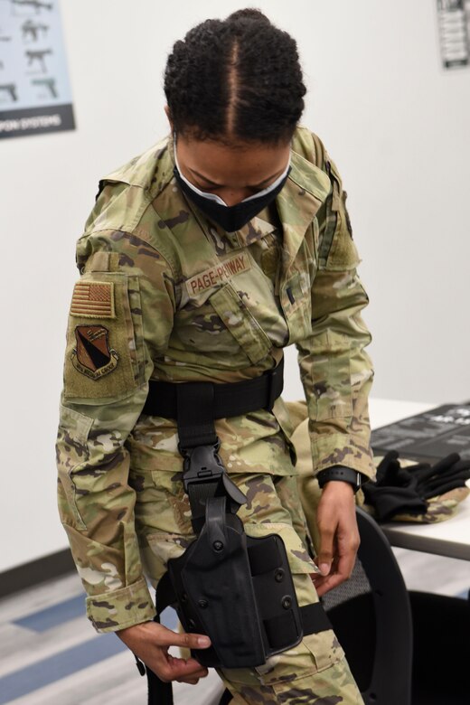 Air Force 1st Lt. Elisabeth Page-Pettiway an 88th Medical Group executive officer, straps on an M9 pistol holster during a qualification course at Wright-Patterson Air Force Base, Ohio on Feb. 18, 2021. Weapons qualification is part of the readiness standards for the 88th Air Base Wing. No live ammunition is allowed in the classroom portion of the qualification course. (U.S. Air Force photo by Ty Greenlees)