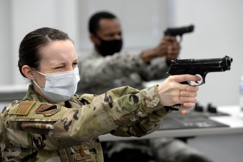 Air Force 2nd Lt. Mariah Armstrong, an 88th Medical Group critical care nurse, left, and SSgt. Stephen Osborne, an 88th Health Care Operations Squadron respiratory therapist, practice sighting and aiming their M9 pistols during a qualification course at Wright-Patterson Air Force Base, Ohio on Feb. 18, 2021. Weapons qualification is part of the readiness standards for the 88th Air Base Wing. No live ammunition is allowed in the classroom portion of the qualification course. (U.S. Air Force photo by Ty Greenlees)