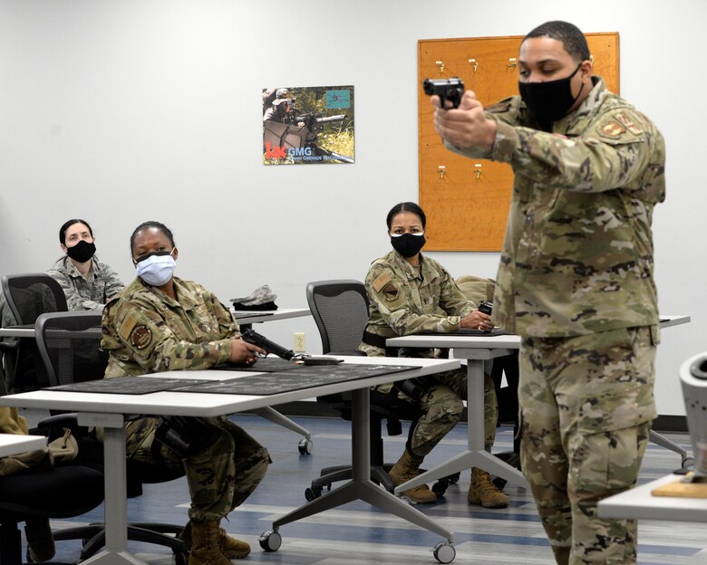 Air Force Senior Airman Jerome Fogg, an 88th Security Forces Squadron combat arms instructor, teaches sighting and posture for the M9 pistol during a qualification course at Wright-Patterson Air Force Base, Ohio on Feb. 18, 2021. Weapons qualification is part of the readiness standards for the 88th Air Base Wing. No live ammunition is allowed in the classroom portion of the qualification course. (U.S. Air Force photo by Ty Greenlees)