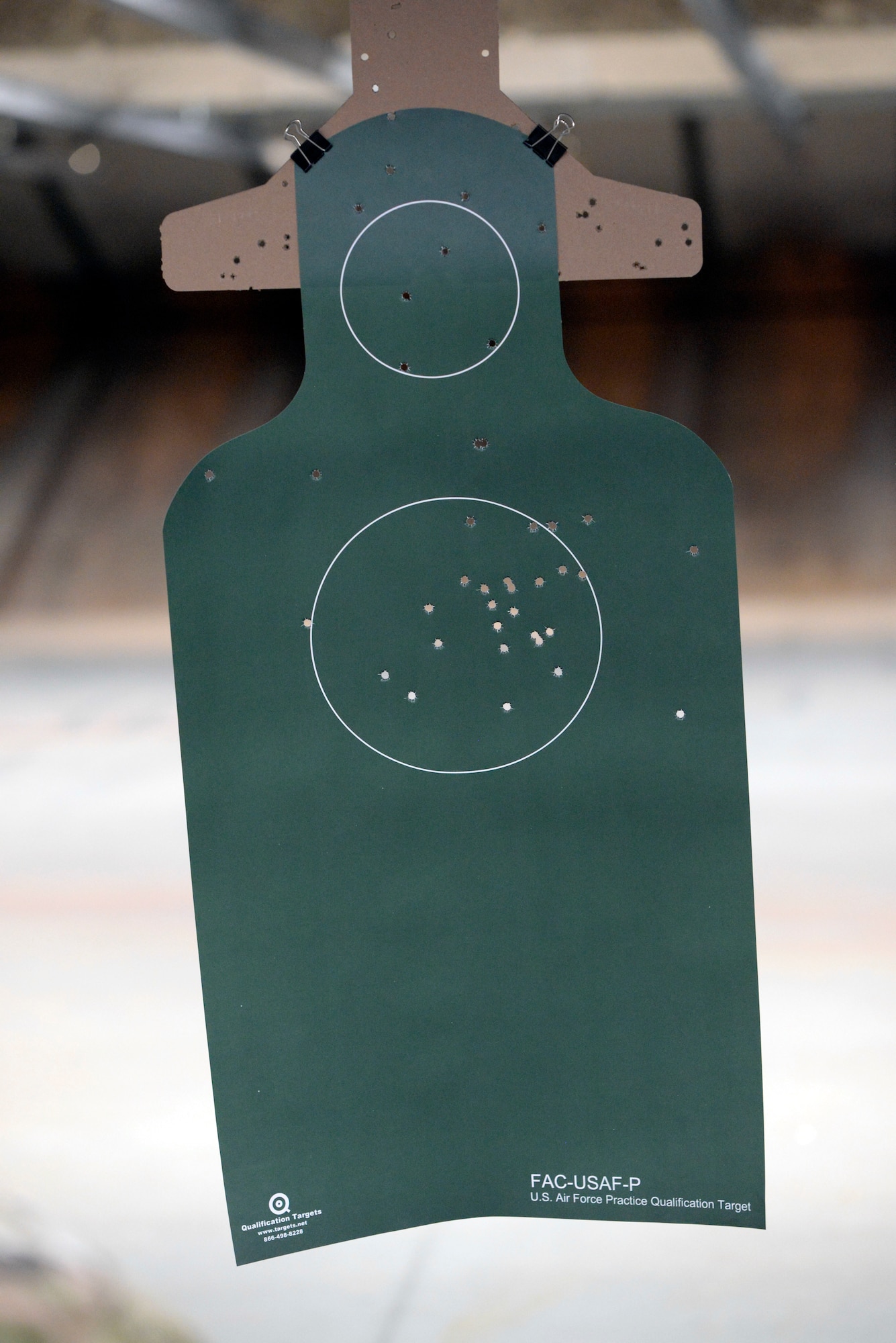 A paper target shot by Air Force 2nd Lt. Mariah Armstrong, an 88th Medical Group critical care nurse, hangs down range during qualification on the M9 pistol inside the 88th Security Forces Squadron Combat Arms firing range at Wright-Patterson Air Force Base, Ohio on Feb. 18, 2021. Weapons qualification is part of the readiness standards for the 88th Air Base Wing. (U.S. Air Force photo by Ty Greenlees)