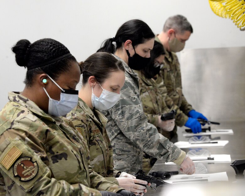 Personnel with the 88th Medical Group clean their M9 pistols after qualifying at the 88th Security Forces Squadron Combat Arms firing range at Wright-Patterson Air Force Base, Ohio on Feb. 18, 2021. Weapons qualification is part of the readiness standards for the 88th Air Base Wing. (U.S. Air Force photo by Ty Greenlees)