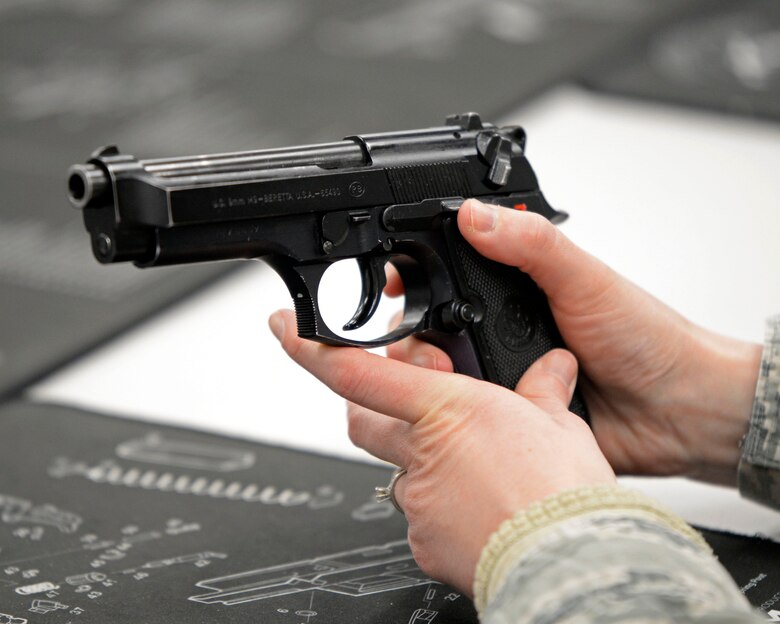 Air Force Maj. Veronika Smith, an 88th Medical Group physical therapist, studies the M9 pistol during a qualification course at Wright-Patterson Air Force Base, Ohio on Feb. 18, 2021. Weapons qualification is part of the readiness standards for the 88th Air Base Wing. No live ammunition is allowed in the classroom portion of the qualification course. (U.S. Air Force photo by Ty Greenlees)