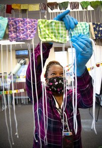 Motisola McKinnon, Competency Specialist with Command University at Puget Sound Naval Shipyard & Intermediate Maintenance Facility in Bremerton, Washington, hangs "Home Team" masks to dry after they were laundered. An April 5, 2020, mandate from then-Defense Secretary Mark Esper required anyone on Department of Defense property to use a protective facemask. Pre-cut, patterned materials and instructions were provided to volunteers who had access to a sewing machine and a pair of scissors in order to produce masks quickly and efficiently. More than 100 volunteers from the shipyard offered to help sew, including employees like McKinnon who were teleworking and joined the cause to assemble masks.