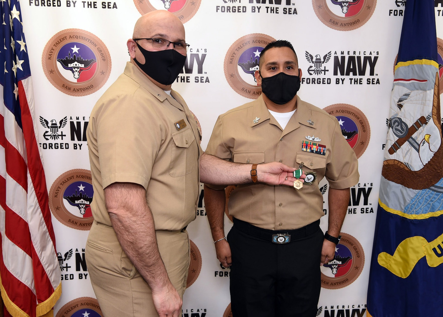 Petty Officer 1st Class Christopher Thomas (right), an officer programs recruiter assigned to Talent Acquisition Onboarding Center Alamo City, was awarded the Navy and Marine Corps Commendation Medal by Rear Adm. Dennis Velez, commander, Navy Recruiting Command at Navy Talent Acquisition Group San Antonio headquarters March 9.  Thomas earned the award for being NRC’s National Nuclear Propulsion Officer Candidate Recruiter of the Year for Fiscal Year 2020.