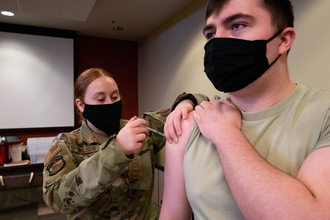 Airmen 1st Class Natalie Wilson, a medical technician from the 28th Healthcare Operations Squadron, administers a second COVID-19 vaccine to Airman 1st Class Tresten Mashtare, a 28th Operations Support Squadron air traffic controller, at the Installation Deployment Readiness Center on Ellsworth Air Force Base, S.D., Feb. 11, 2021. Beneficiaries and base personnel who have not received the Pfizer COVID-19 vaccines previously will have the opportunity to receive their initial (or second for those who have already received their first through the 28th Medical Group) dose March 19, at a point of distribution (POD) site in the base IDRC. (U.S. Air Force photo by Staff Sgt. Hannah Malone)