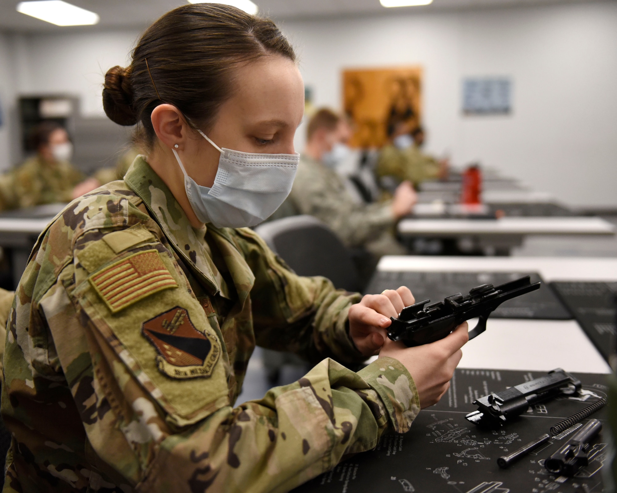 Air Force 2nd Lt. Mariah Armstrong, an 88th Medical Group critical care nurse, practices disassembling the M9 pistol during a qualification course at Wright-Patterson Air Force Base, Ohio on Feb. 18, 2021. Weapons qualification is part of the readiness standards for the 88th Air Base Wing. No live ammunition is allowed in the classroom portion of the qualification course. (U.S. Air Force photo by Ty Greenlees)