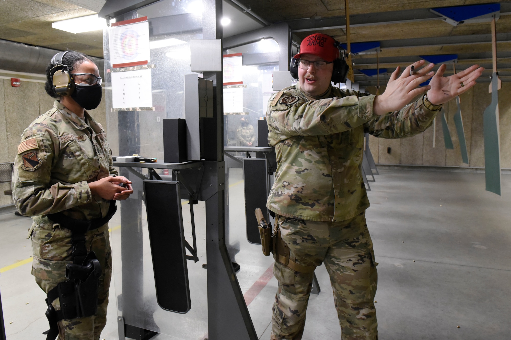 Air Force Senior Airman Clayton Nyp, an 88th Security Forces Squadron combat arms instructor, right, works with 1st Lt. Elisabeth Page-Pettiway an 88th Medical Group executive officer, as she qualifies with the M9 pistol inside the 88th Security Forces Squadron Combat Arms firing range at Wright-Patterson Air Force Base, Ohio on Feb. 18, 2021. Weapons qualification is part of the readiness standards for the 88th Air Base Wing. (U.S. Air Force photo by Ty Greenlees)