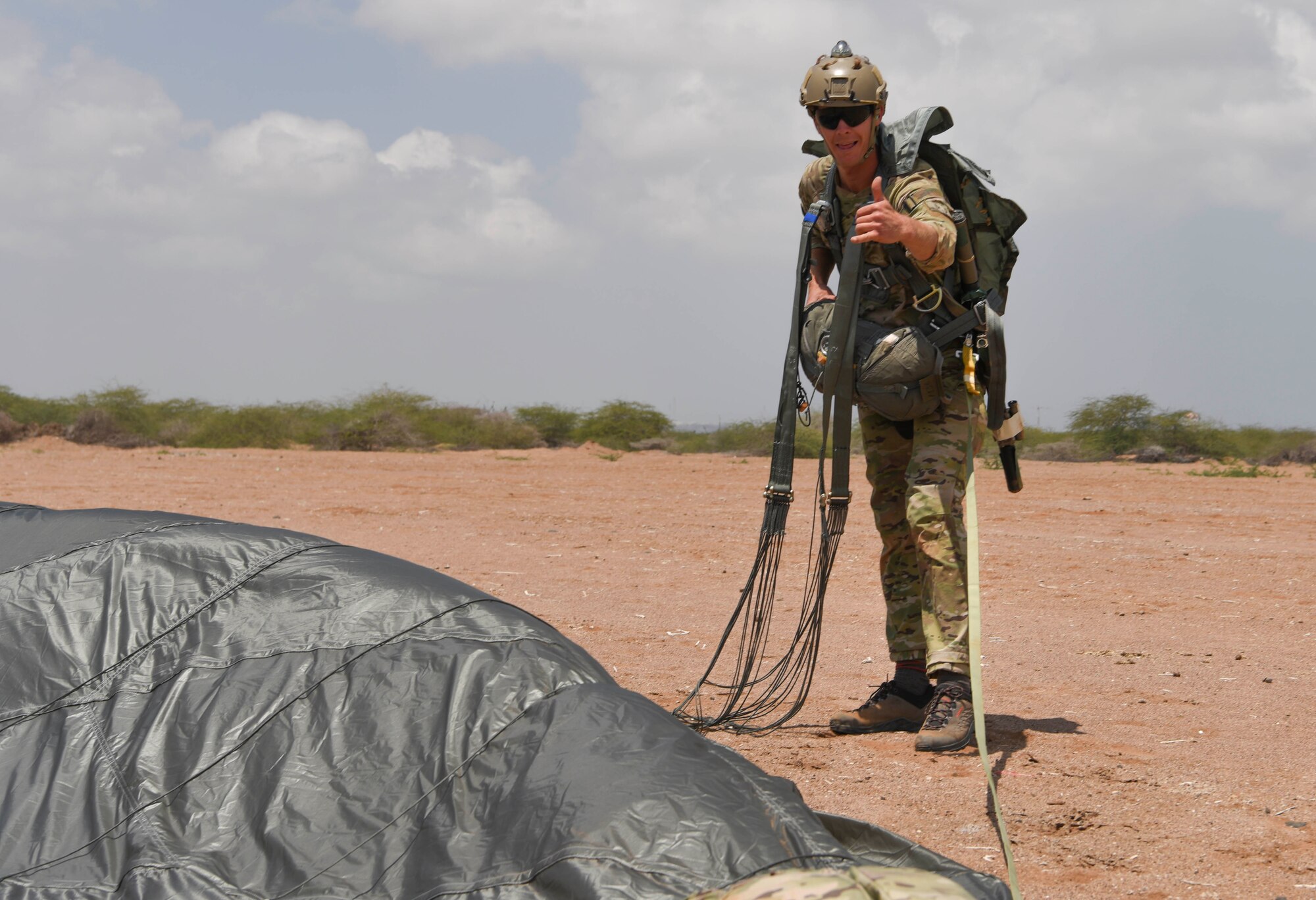 A U.S. Air Force pararescueman assigned to the 82nd Expeditionary Rescue Squadron, gives a shaka sign after completing a jump at Camp Lemonnier, Djibouti, March 16, 2021.