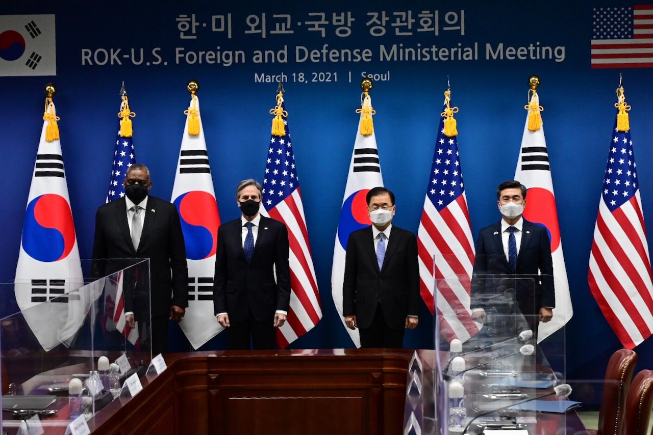 American and South Korean leaders stand for a photo in front of country flags.