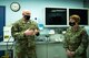 Two Airmen sit at a desk.