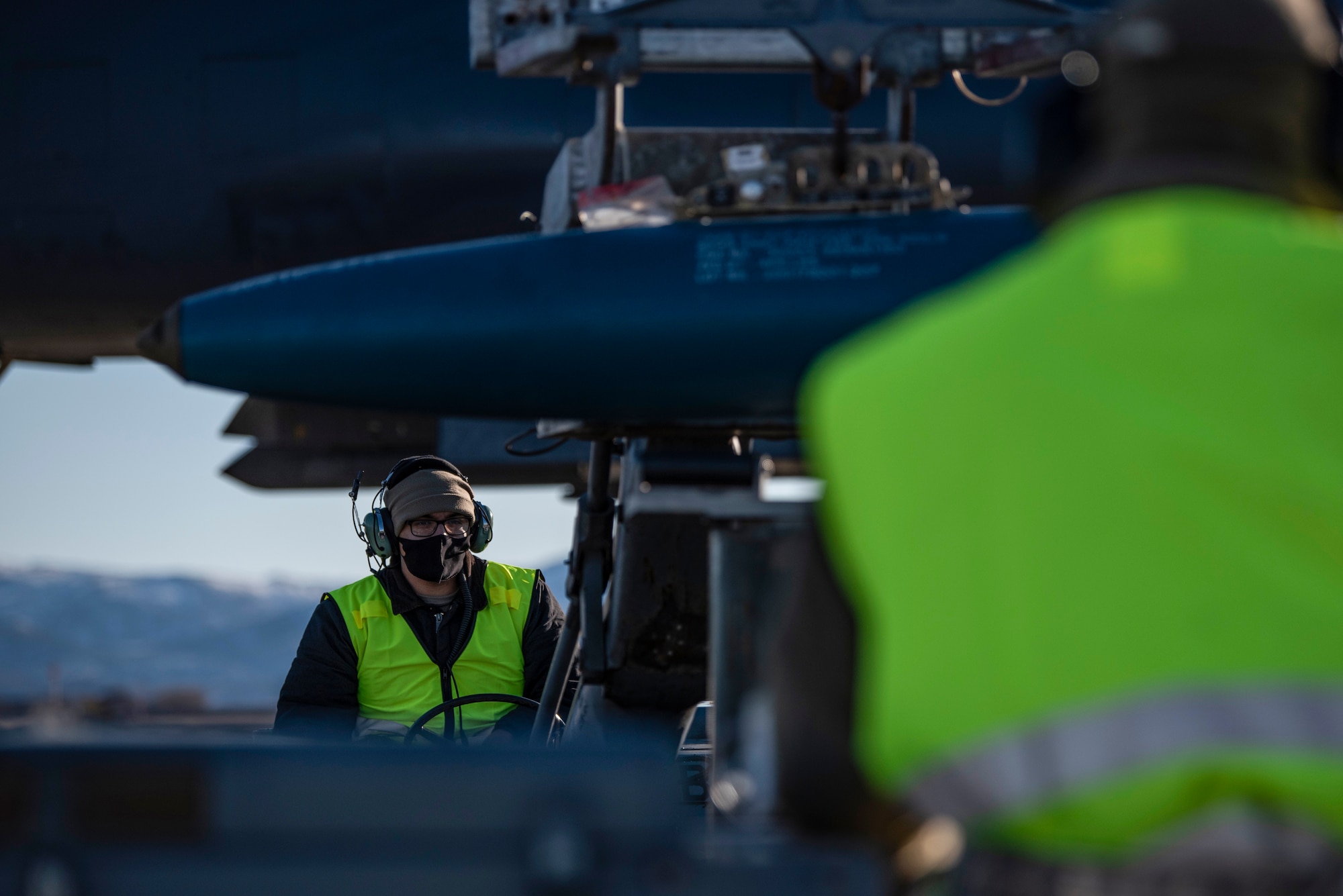 Two weapons load crew members assigned to the 9th Expeditionary Bomb Squadron operate MHU-83 jammers carrying a bomb dummy unit at Ørland Air Force Station, Norway, March 13, 2021. Two jammers are utilized during the weapons loading of the bomber. One securely lifts the munition off of the bomb cart and transfers it to the second jammer that subsequently lifts the ordinance into the bomb-bay. (U.S. Air Force photo by Airman 1st Class Colin Hollowell)