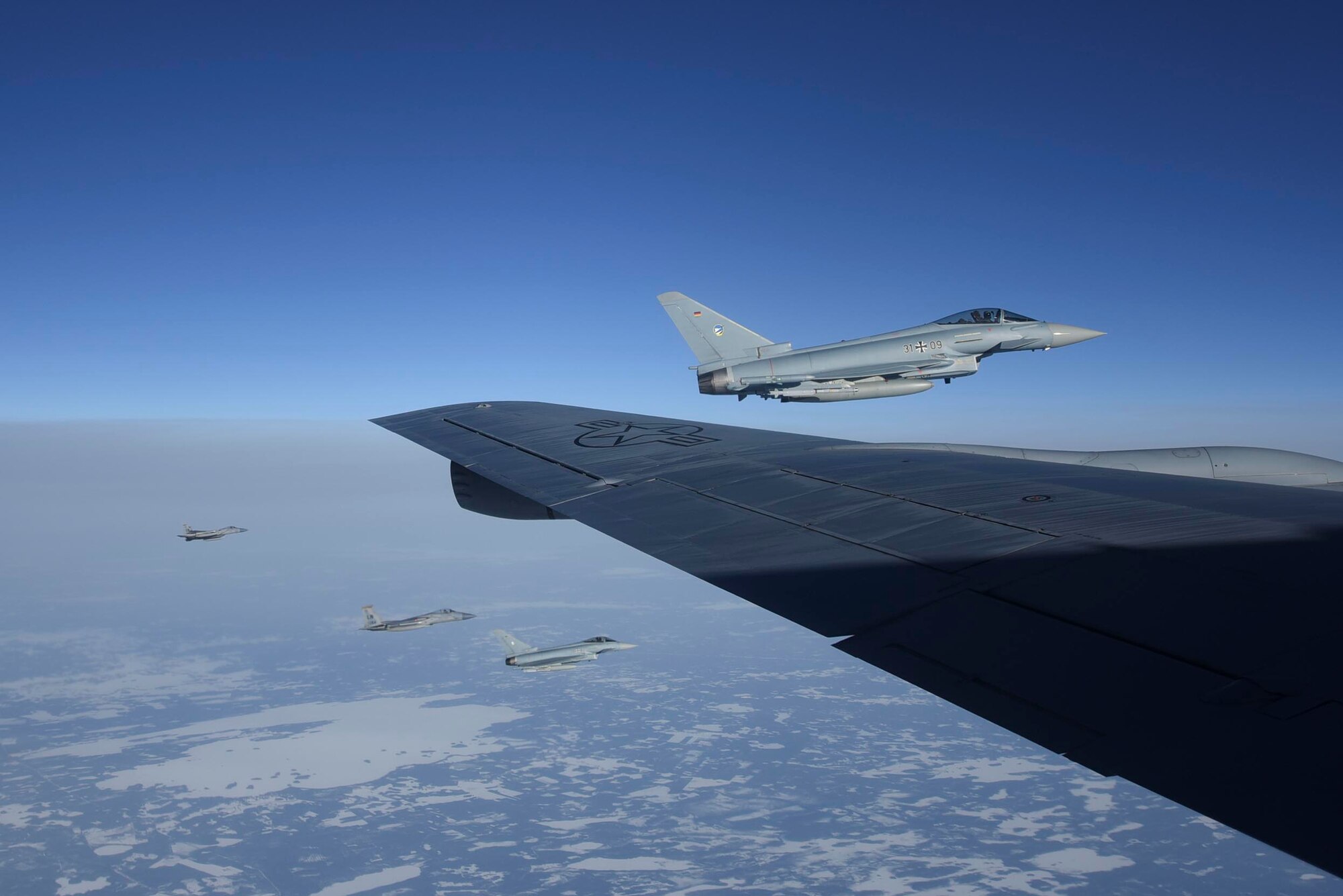Two German air force EF-2000 Typhoon aircraft and two U.S. Air Force F-15C Eagle aircraft assigned to the 493rd Fighter Squadron, fly alongside a KC-135 Stratotanker aircraft over Finland during exercise Baltic Trident, March 17, 2021. Training with joint and combined allies and partners during agile combat employment events increases lethality and enhances interoperability, allowing forces to counter military aggression and coercion by sharing responsibilities for common defense. (U.S. Air Force photo by Senior Airman Joseph Barron)