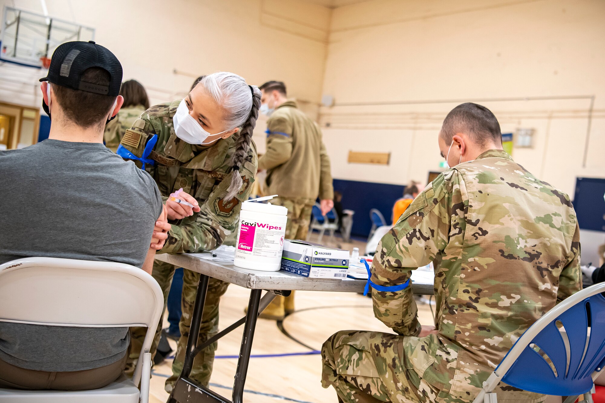 Master Sgt. Jessica Scherette, center, 501st Combat Support Wing, Inspector General inspection team member, administers the COVID-19 vaccine during a mass vaccination line at RAF Alconbury, England, Mar. 18, 2021. This is the first time the 501st CSW has conducted a mass-vaccination line and are expected to vaccinate approximately 300 people. Multiple Airmen and civilians from the 423rd Medical, Civil Engineering, Emergency management and Communication squadrons assisted in helping vaccines be distributed to the pathfinder community. (U.S. Air Force photo by Senior Airman Eugene Oliver)