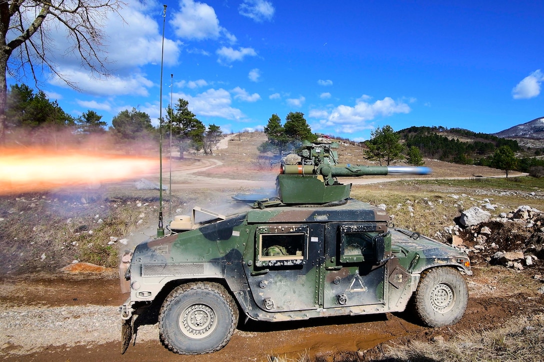 Soldiers fire a missile from a Humvee in a field.