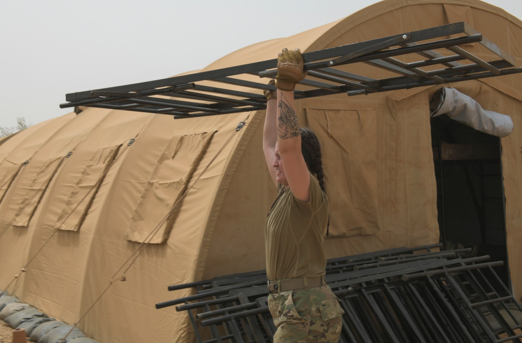 U.S. Air Force Senior Airman Madison Morgan, 768th Expeditionary Air Base Squadron Base Exchange manager, removes broken bunk beds from a transient tent at Nigerien Air Base 101, Niamey, Niger, Feb. 17, 2021. A total of 30 bed frames were replaced in support of a surge of deployed members to Air Base 101. (U.S. Air Force photo by Senior Airman Gabrielle Winn)