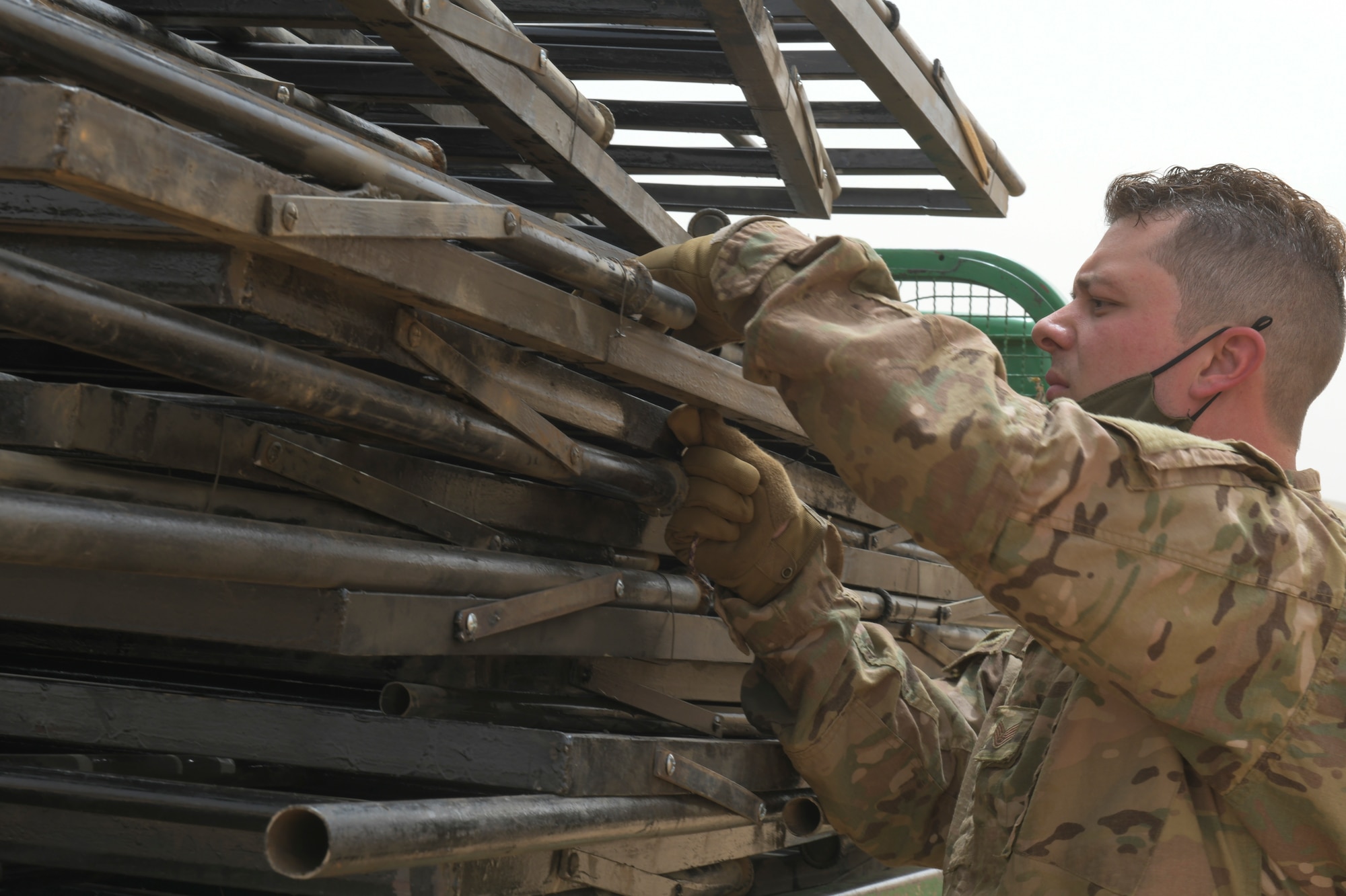 U.S. Air Force Staff Sgt. Casey Barron, 768th Expeditionary Air Base Squadron postmaster, ties down broken bunk bed frames with paracord onto the back of a pickup truck at Nigerien Air Base 101, Niamey, Niger, Feb. 17, 2021. A total of 30 bed frames were replaced in support of a surge of deployed members to Air Base 101. (U.S. Air Force photo by Senior Airman Gabrielle Winn)