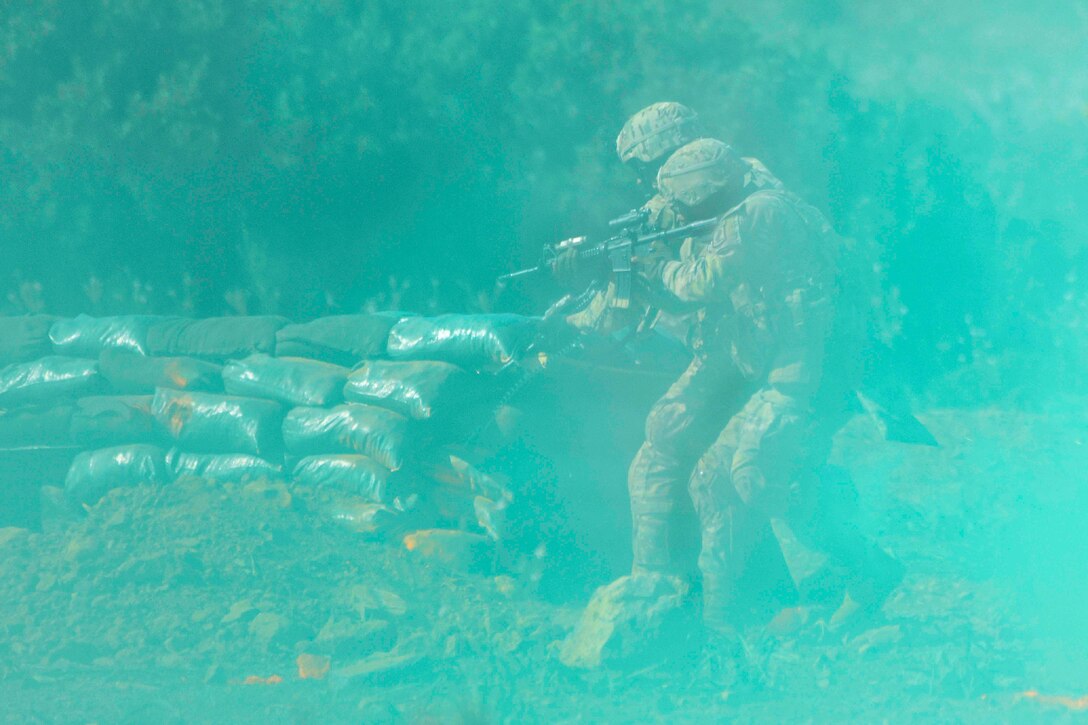 Two soldiers fire at a target as green smoke surrounds them.