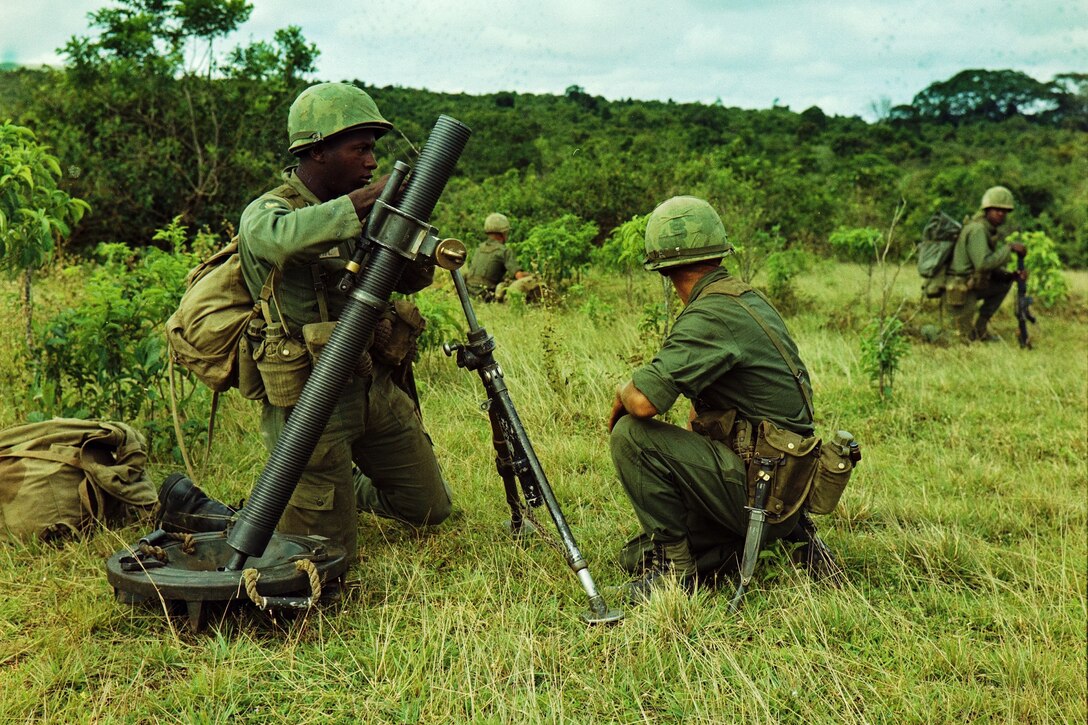 Soldiers prepare their mortar for action in a small field.
