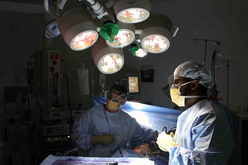 Two sailors perform surgery in Afghanistan.