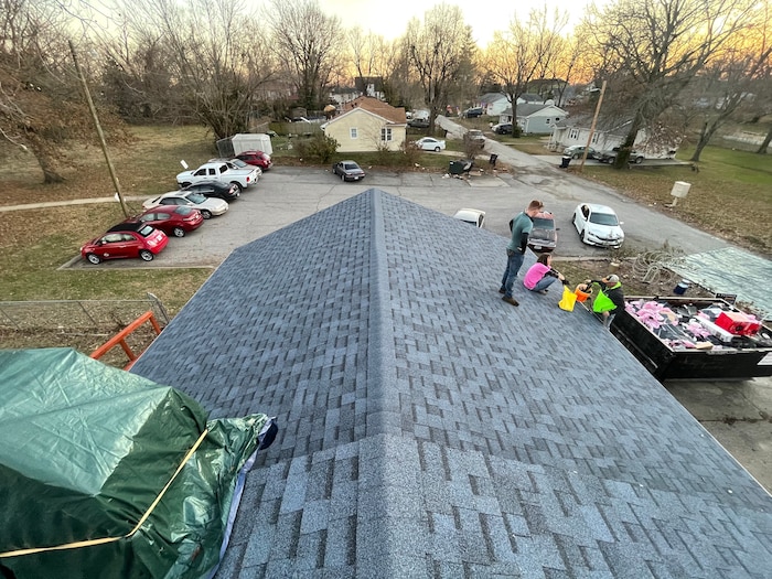 The mostly completed roof of a local family's house with volunteers completing work on it.