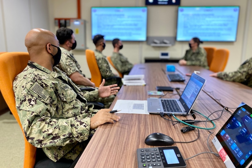 Multiple military personnel sit at a long table.