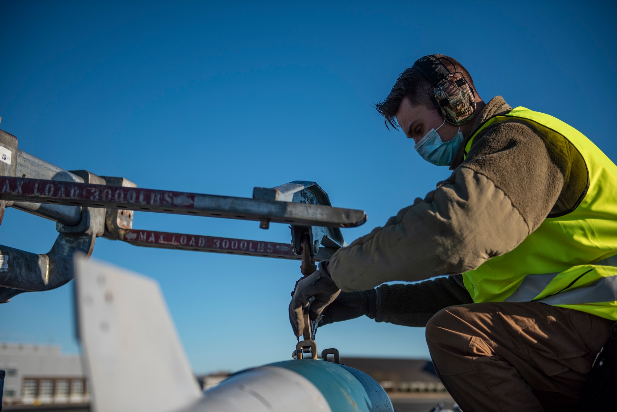 A weapons load crew team chief assigned to the 9th Expeditionary Bomb Squadron secures a bomb dummy unit to a MHU-83 jammer at Ørland Air Force Station, Norway, March 13, 2021. The weapons load crew team members loaded eight BDUs into a B-1B Lancer prior to aircrew conducting a Bomber Task Force Europe training mission. (U.S. Air Force photo by Airman 1st Class Colin Hollowell)