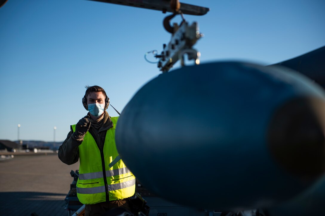 A weapons load crew team chief assigned to the 9th Expeditionary Bomb Squadron guides a bomb dummy unit at Ørland Air Force Station, Norway, March 13, 2021. Weapons load crew members routinely conduct munitions load training to maintain safety and proficiency standards. (U.S. Air Force photo by Airman 1st Class Colin Hollowell)