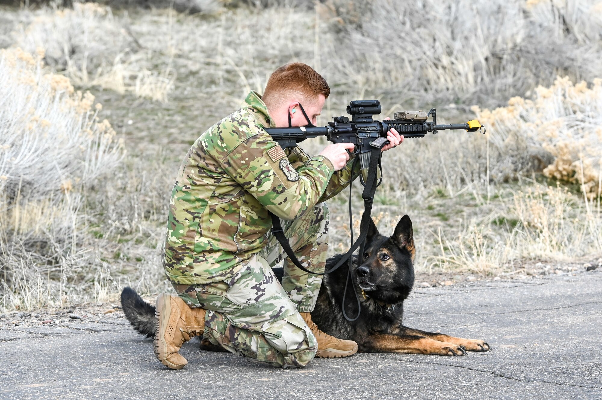 Staff Sgt. Patrick Cushing, a military working dog handler with the 75th Security Forces Squadron, fires a weapon during training March 10, 2021, at Hill Air Force Base, Utah, in order for MWD Jimo to become accustomed to the noise. MWD Jimo is an explosive detection dog. (U.S. Air Force photo by Cynthia Griggs)