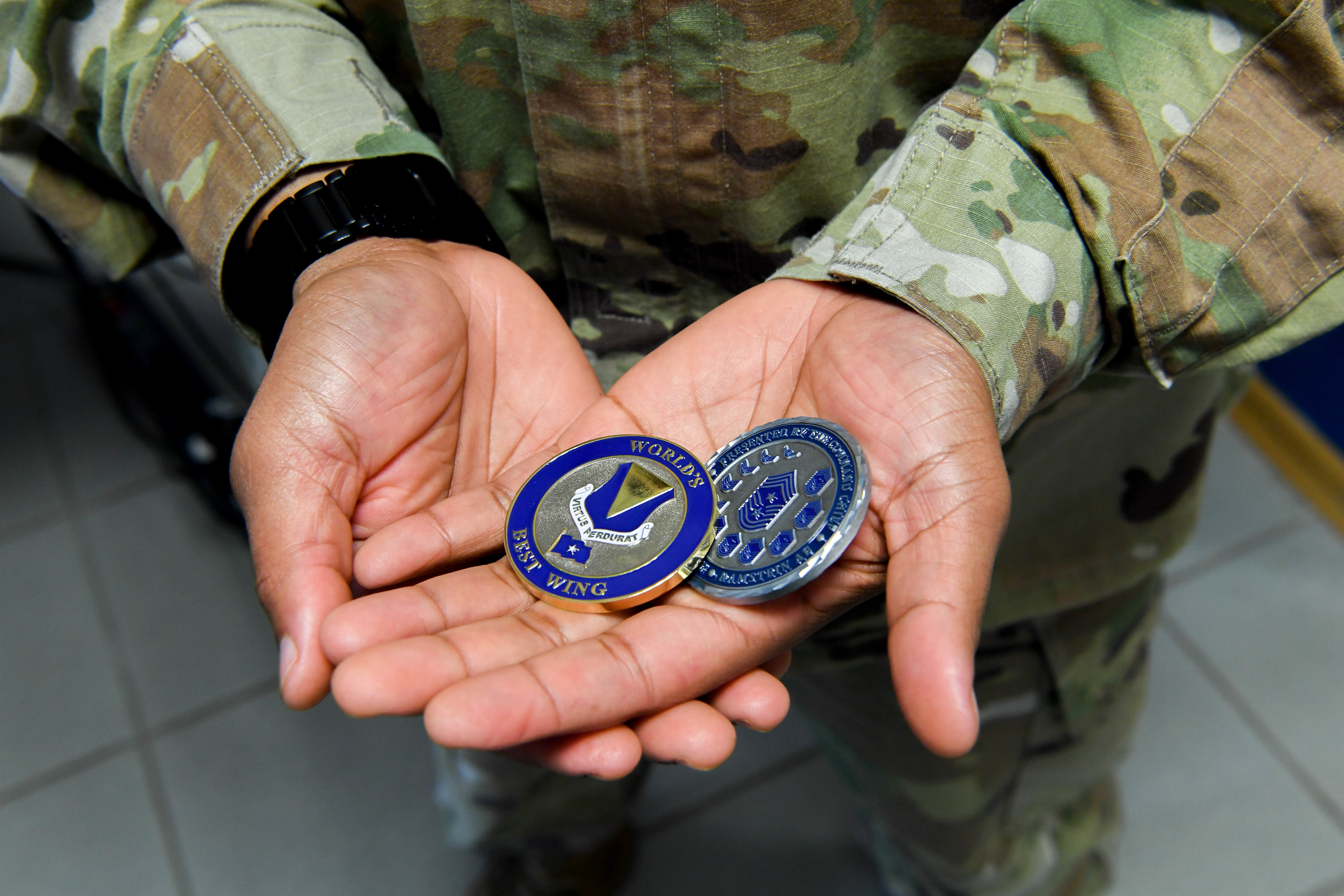 An Airman displaying his Airlifter of the Week coins.