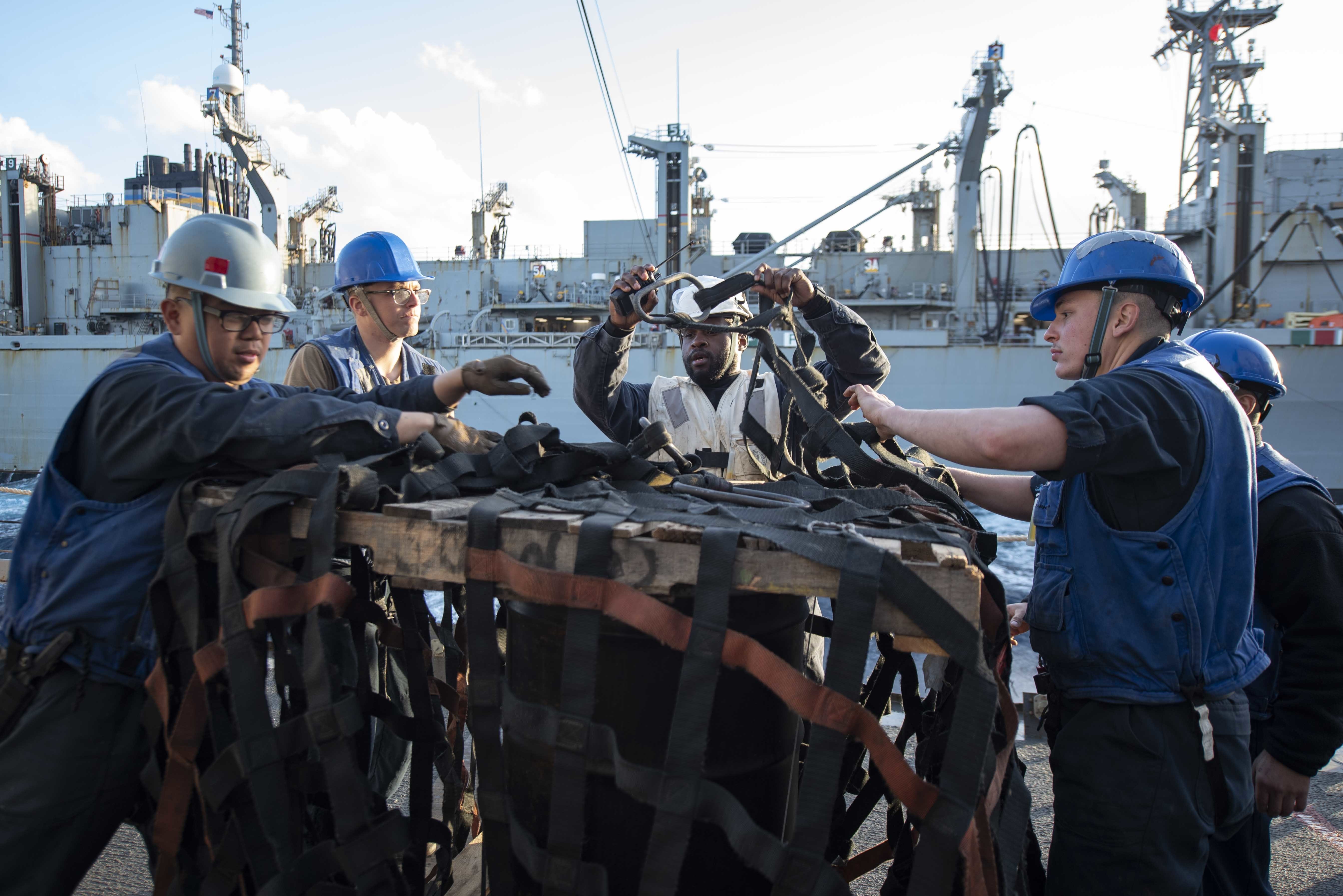 Sailors prepare a pallet for transport aboard USS Mitscher (DDG 57) during a replenishment-at-sea with the Supply-class fast combat supply support ship USNS Arctic (T-AOE 8), March 16, 2021.