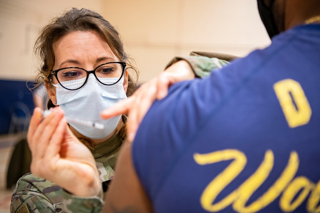 Lt. Col. Elizabeth Hoettels, left, 423rd Medical Squadron commander, administers the COVID-19 vaccine during a mass vaccination line at RAF Alconbury, England, Mar. 18, 2021. This is the first time the 501st CSW has conducted a mass-vaccination line and are expected to vaccinate approximately 300 people. Multiple Airmen and civilians from the 423rd Medical, Civil Engineering, Emergency management and Communication squadrons assisted in helping vaccines be distributed to the pathfinder community. (U.S. Air Force photo by Senior Airman Eugene Oliver)
