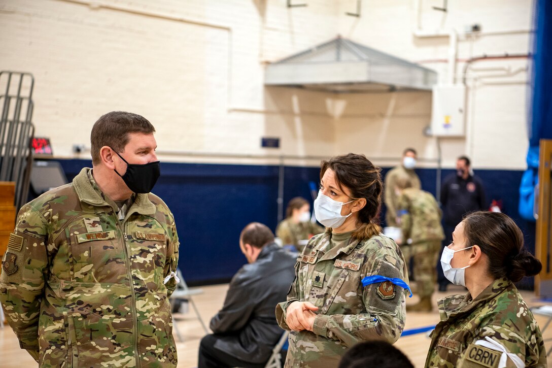 Col. Kurt Wendt, left, 501st Combat Support Wing commander, speaks with Lt. Col. Elizabeth Hoettels, center, 423rd Medical Squadron commander, and Master Sgt. Terri Adams, right, 423rd Civil Engineering squadron NCO in charge of Emergency management during a mass COVID-19 vaccination line at RAF Alconbury, England, Mar. 18, 2021. This is the first time the 501st CSW has conducted a mass-vaccination line and are expected to vaccinate approximately 300 people. Multiple Airmen and civilians from the 423rd Medical, Civil Engineering, Emergency management and Communication squadrons assisted in helping vaccines be distributed to the pathfinder community. (U.S. Air Force photo by Senior Airman Eugene Oliver)