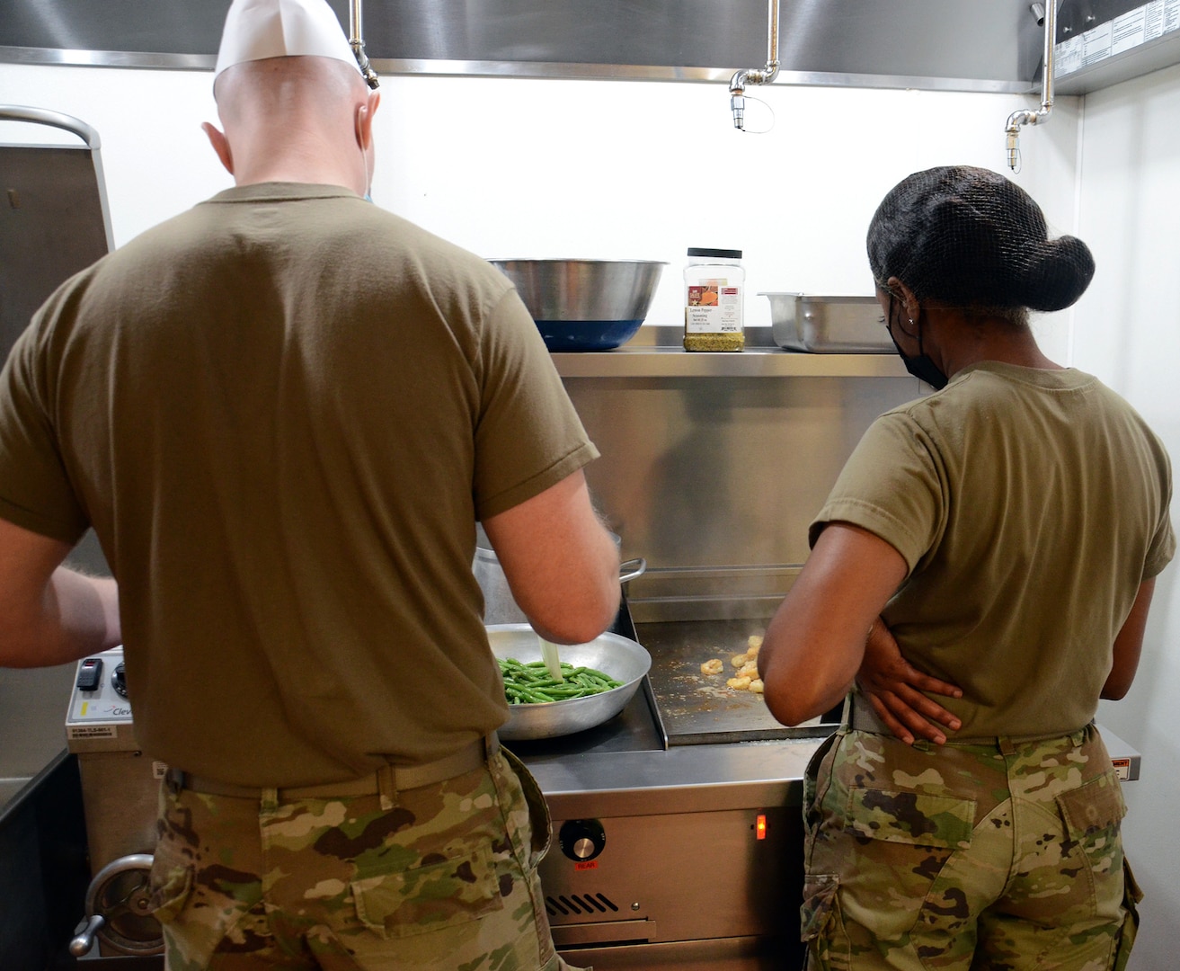 Nutrition and Diet Therapy program students Staff Sgt. Mathew Kensecki (left) and Airman 1st Class Marissa Stove (right) practice cooking during an Air Force food production course conducted in the kitchen training laboratory.