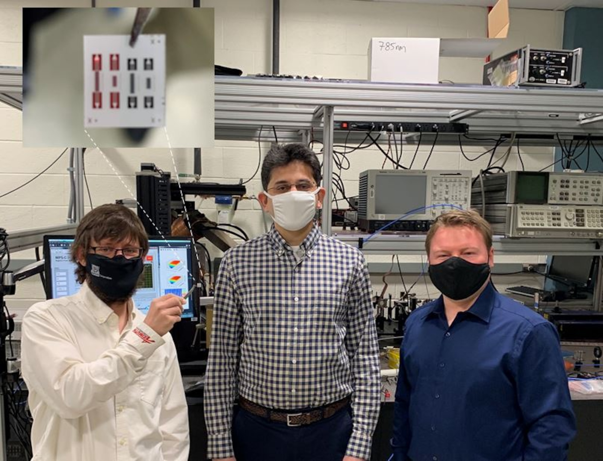 From the left to right, Drs. Derek A. Bas, Piyush J. Shah and Michael R. Page. In the tweezers, Bas is holding a chip that contains an array of four isolators. A state-of the-art commercial RF isolator has a much greater size and weight than the AFRL device. (U.S. Air Force photo/Dr. Michael Wolf)
