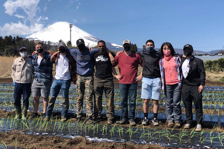 御殿場市内にある野菜畑で３月１４日、キャンプ富士の海兵隊員たちは玉ねぎの苗を一つ一つ手に取り、畑に小さな穴を掘って苗を手作業で丁寧に植えつけ、作業後にみんなで記念撮影